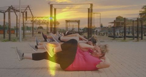 Group of Women Performing Bicycle Crunches at Fitness Park Sunset