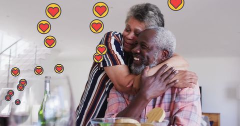 Happy Senior Couple Embracing at Home with Heart Icons