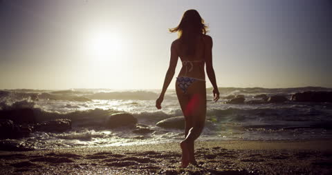 Serene Beach Sunset with Woman Strolling on Sand