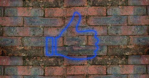 Glowing Digital Thumbs Up Symbol Against Brick Wall Background