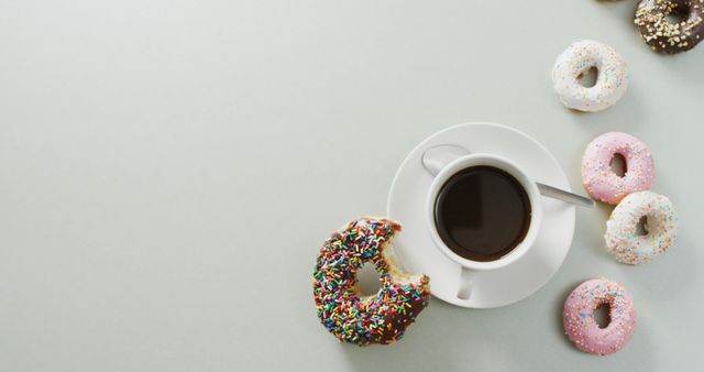 Coffee with a variety of colorful donuts featuring sprinkles and different icing options. Suitable for advertisements, blog posts, and social media content related to breakfast, dessert, and coffee culture.