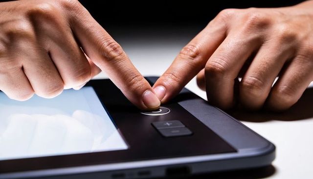 Close-up hands adjusting metallic dial on digital drawing tablet for precision control