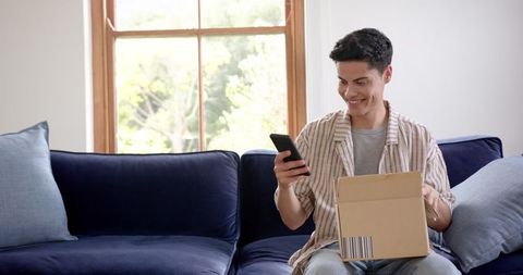Happy man unboxing parcel with smartphone