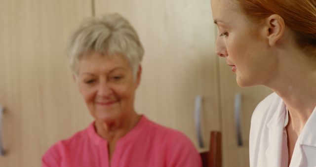 Caregiver having a gentle conversation with a senior woman in a home setting. Useful for themes related to eldercare, nursing, healthcare support, senior living, and the caregiver-patient relationship.