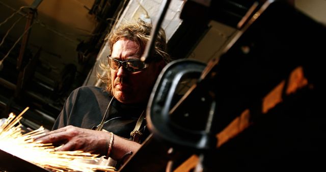 Middle-aged man grinding metal with sparks flying in workshop - Download Free Stock Images Pikwizard.com