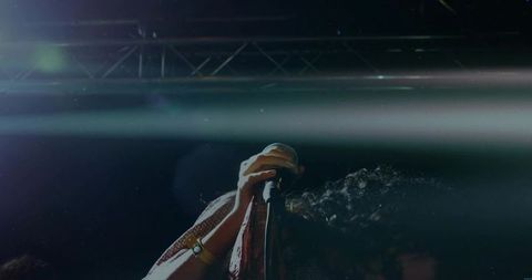 Female singer gripping microphone and stand under dramatic stage light beams