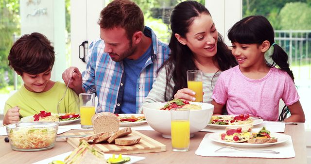 Parents and children are around the dining table, sharing a cheerful breakfast. The scene conveys warmth, togetherness, and healthy living. Ideal for promoting family values, healthy eating habits, and quality time spent with loved ones.