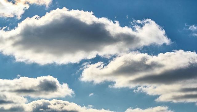 Drifting Cumulus Clouds Casting Soft Shadows Across Bright Blue Sky