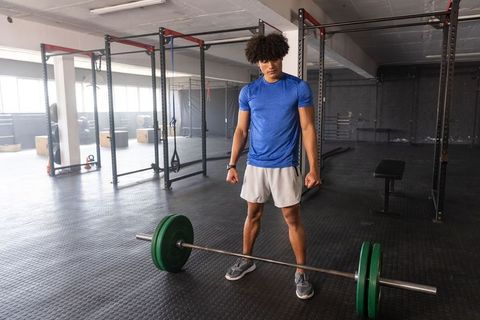 Male athlete preparing to deadlift with loaded barbell in modern gym strength training