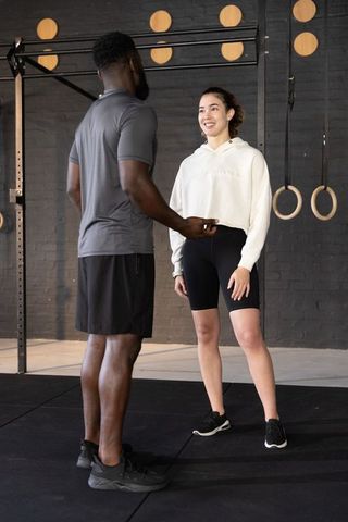 Female client receiving coaching from african-american trainer with timer in gym