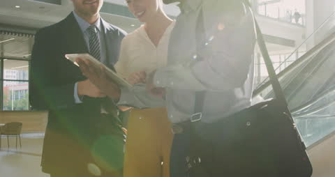 Diverse Business Team Collaborating on Tablet in Office Lobby