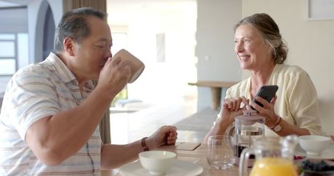 Senior Couple Enjoys Relaxing Breakfast with Smartphone Technology