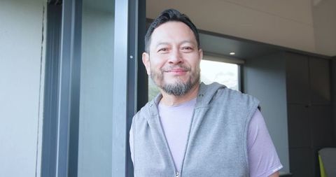 Asian man relaxing by home doorway in modern interior