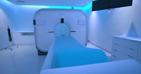 Futuristic mri scanner room with blue led ambient lighting, patient couch and gantry
