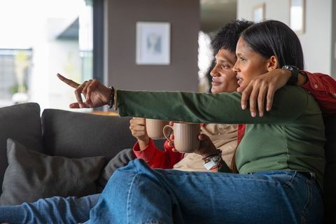 Couple relaxing on sofa with hot drinks in modern living room