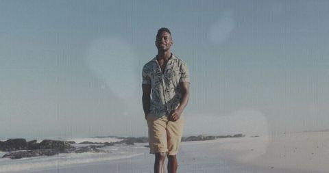 Man Walking by Ocean in Casual Outfit on Sunny Beach Day
