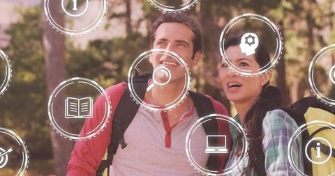 Couple exploring augmented reality trail while hiking with backpacks and ar icons