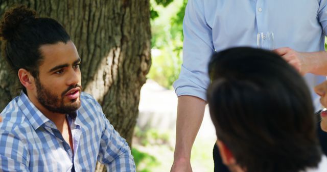 Young Man Discussing Outdoors with Friends on Sunny Day - Download Free Stock Images Pikwizard.com