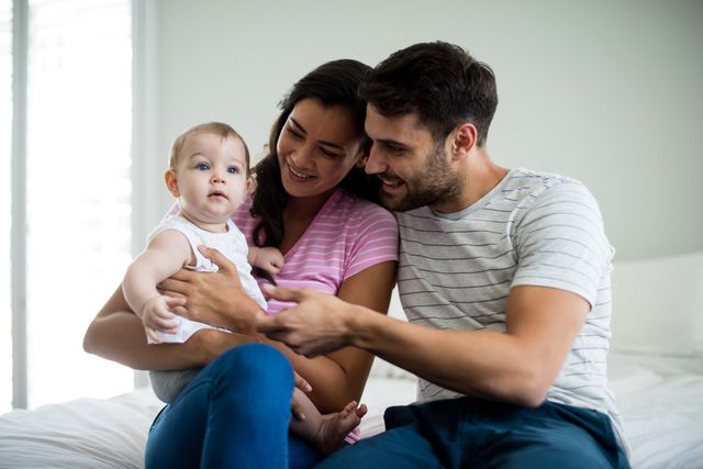 Couple playing with their baby girl on bed at home