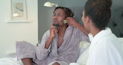 African american couple sharing skincare routine woman applying cooling facial pad to man