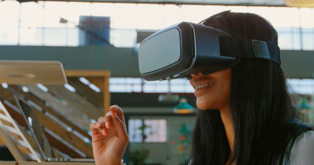 Woman uses virtual reality headset, smiling, engaging in immersive digital experience. Suitable for use in technology, innovation, futuristic experiences, digital interaction, modern lifestyle promotions. Highlights VR, interactive tech.