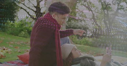 Couple relaxing in park with smartphone and visual overlay