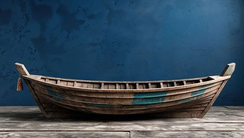 Vintage wooden rowboat against rustic blue wall background