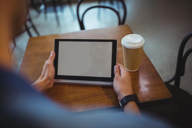 Man using digital tablet while having coffee in cafe