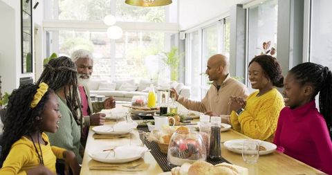 Multigenerational Family Gathering Sharing Meal Around Sunlit Open-Plan Dining Table