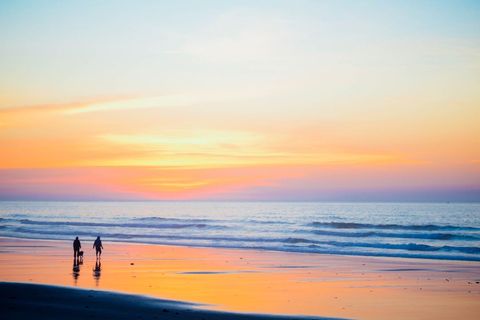 Idyllic Beach Sunrise with Silhouettes of People Walking