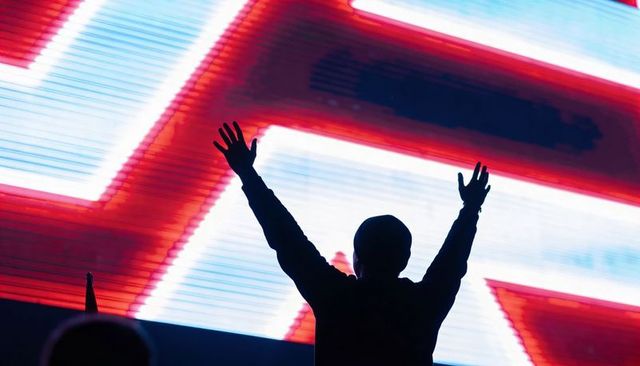 Silhouette raising arms at neon concert led display celebrating crowd energy