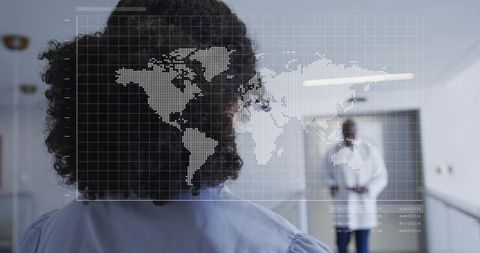 Female clinician reviewing digital map overlay in hospital corridor with doctor behind