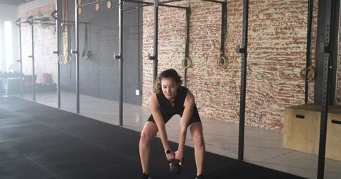 Female Athlete Engaged in Kettlebell Workout in Industrial Gym Setting