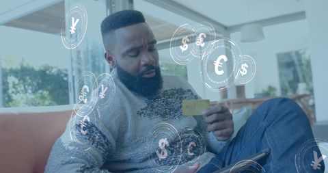 Man using credit card for online transaction with currency symbols displayed