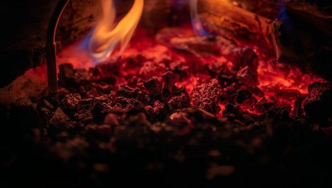 Glowing furnace coals radiating intense heat with blue flames and burner tubes