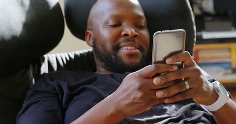 Relaxed Man Texting on Smartphone at Home
