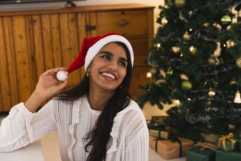 Smiling woman in santa hat by decorated christmas tree