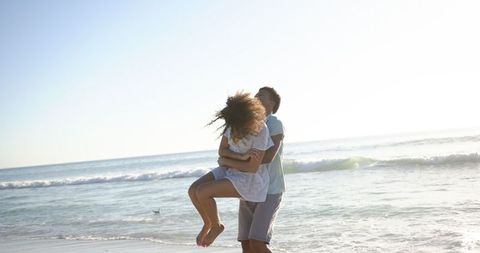 Couple Playing on Sunlit Beach by Sea Waves