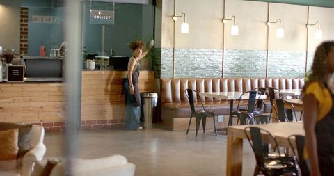 Barista adjusting collect sign behind counter in modern wood and leather coffeehouse cafe