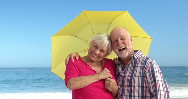Senior couple holding umbrella at the beach