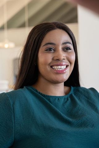 African american woman smiling and posing in teal blouse, confident modern indoor portrait