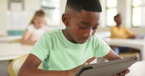 Elementary student using tablet in classroom focusing on digital learning and engagement