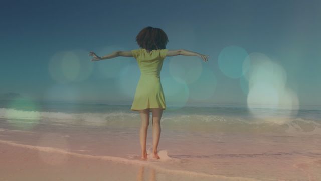 Young African American woman enjoying a sunny day on a tropical beach, raising hands and feeling the freedom and joy of the moment. Perfect for themes involving travel, vacation, fitness, happiness, wellbeing, and nature. Can be used for ads in travel agencies, wellness campaigns, summer promotions or lifestyle blogs.