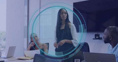 Leading Presentation in Modern Boardroom with Engaged Team Collaborating on Laptops