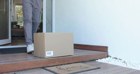 Delivery package left on porch with african american man stepping out in white sneakers
