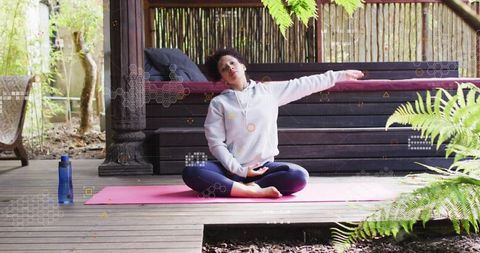 Woman meditating cross-legged on pink yoga mat in wooden pavilion outdoor wellness routine