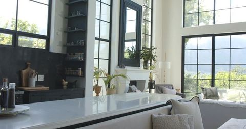 Bright Open-Plan Kitchen Lounge Featuring White Marble Island, Black Grid Windows