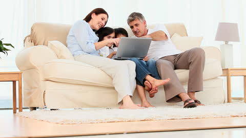 Smiling Family Using Laptop Relaxing on Sofa