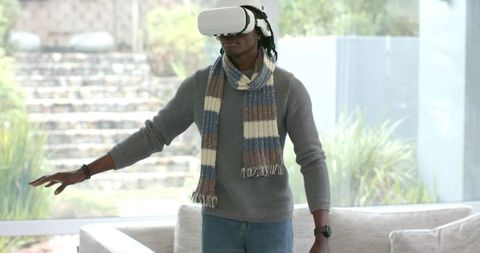 African American man exploring virtual reality wearing VR headset in modern living room