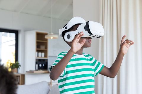 Black boy exploring virtual world with white vr headset in modern living room